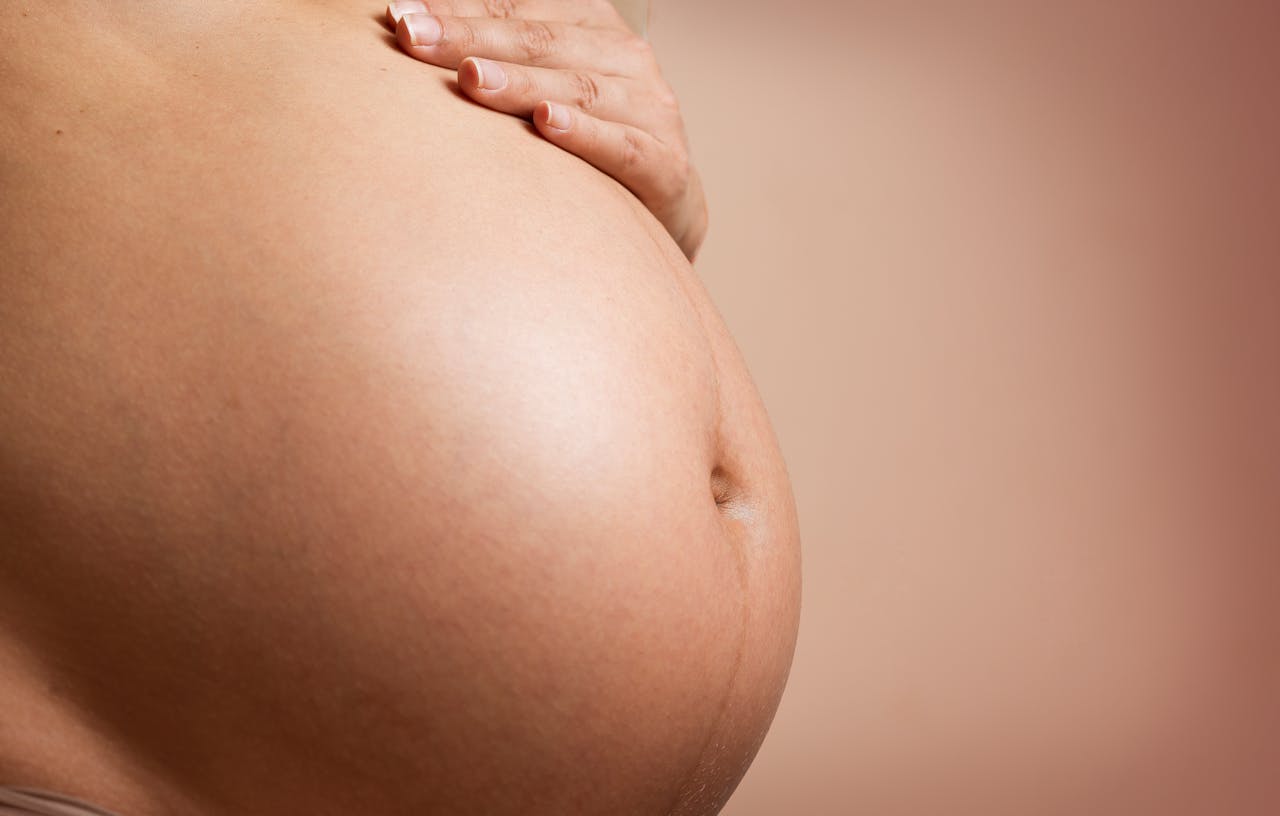 hero-img-01 An intimate close-up of a pregnant woman's abdomen, highlighting maternity and parenthood.