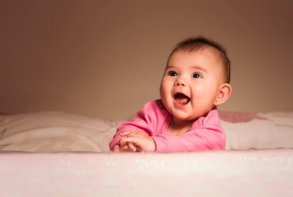 pexels photo 1557182 Charming portrait of a smiling baby girl in pink indoors, exuding happiness and innocence.