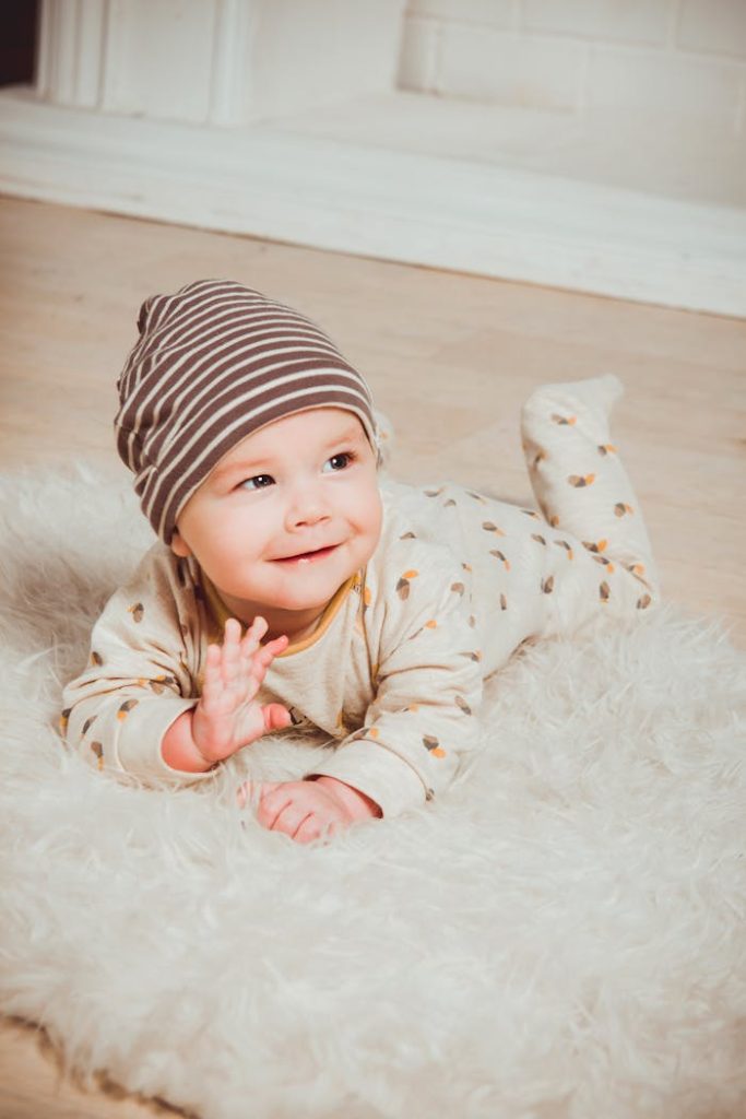 pexels photo 1648377 A cute baby in striped beanie lying on fluffy rug indoors, smiling with innocence.
