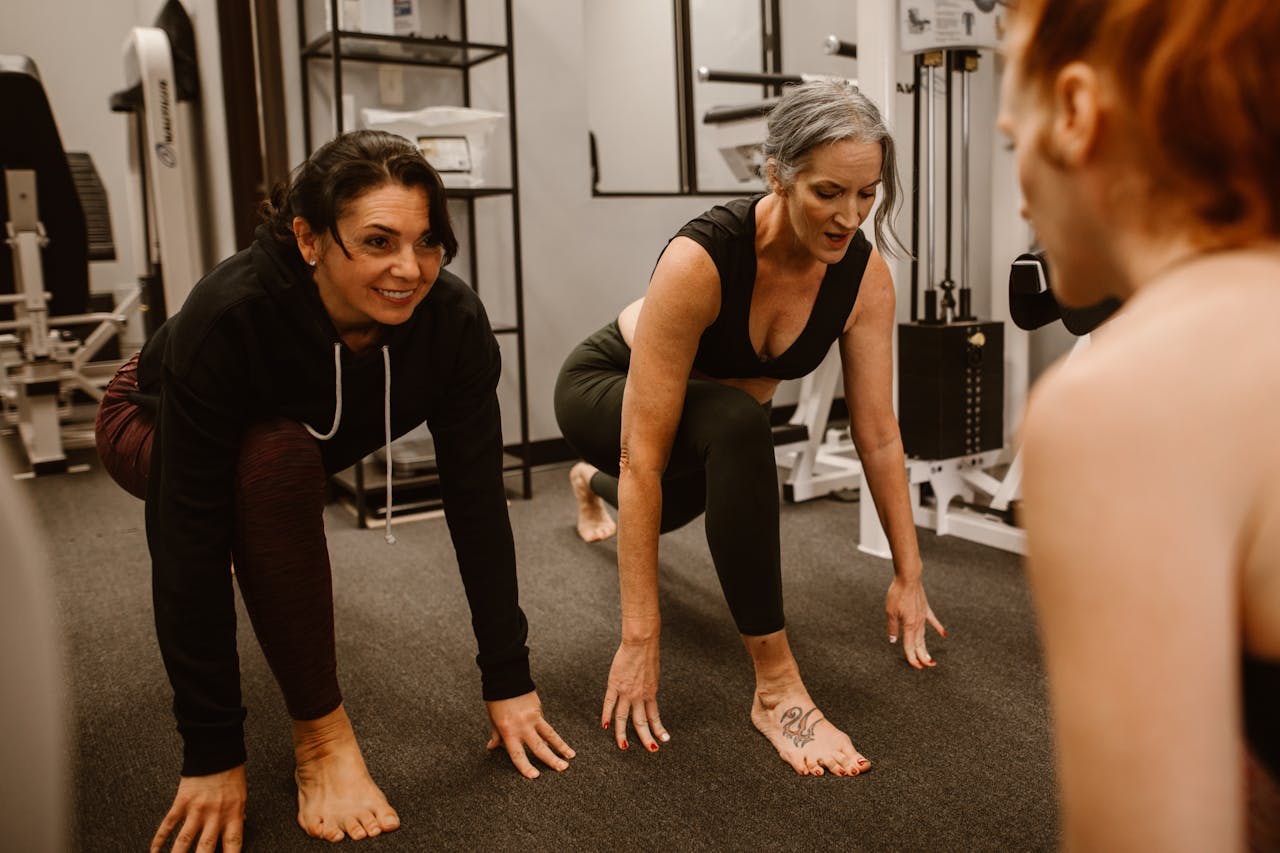 services-01 Three women engaged in a workout session in a gym, focusing on strength and balance.