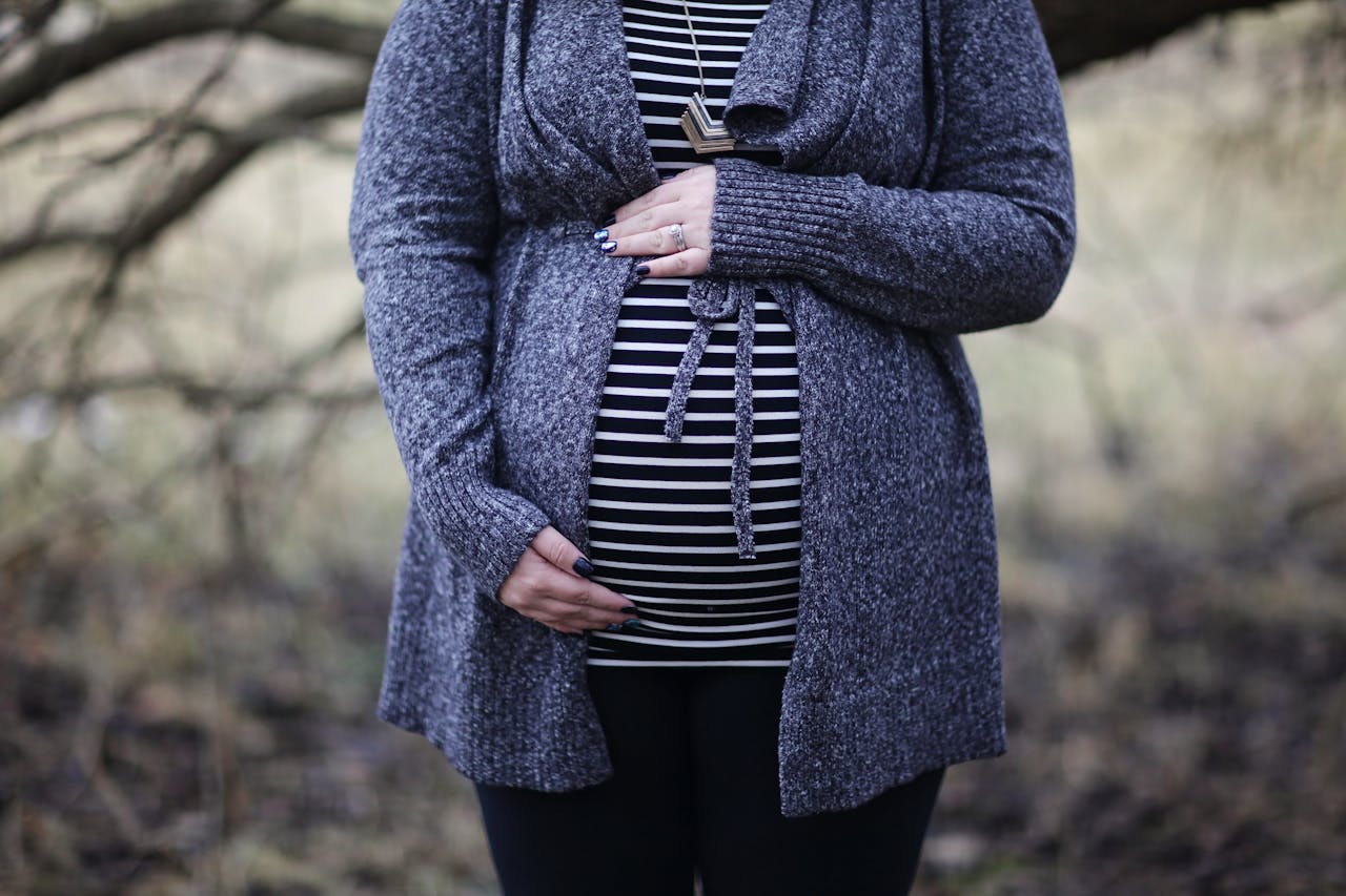 our-services-1 Pregnant woman in striped shirt and cozy sweater outdoors, embracing motherhood.